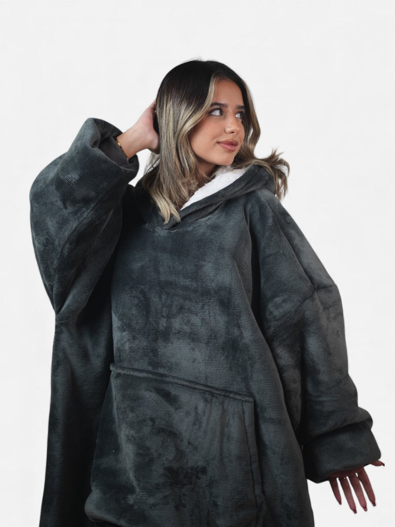Cozify oversized wearable blanket hoodie in charcoal grey with a white sherpa lining and large front pocket, shown close-up on a woman posing against a white background.