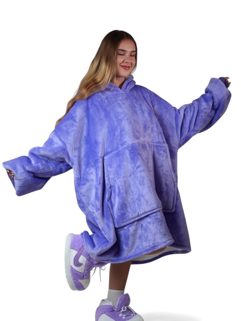 Cozify oversized wearable blanket hoodie in lavender purple with a large front pocket, worn by a smiling woman posing playfully against a white background.