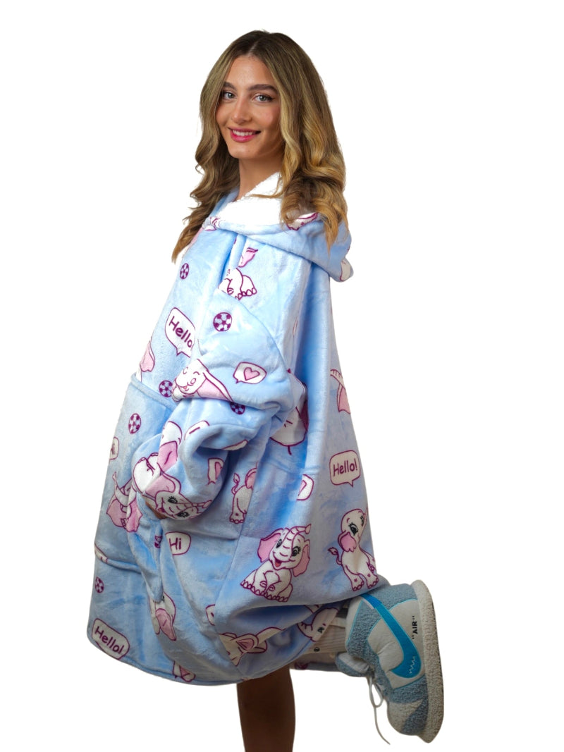 Woman smiling in a side view pose wearing a light blue oversized Cozify hoodie blanket with a pink elephant print and cozy sherpa lining.