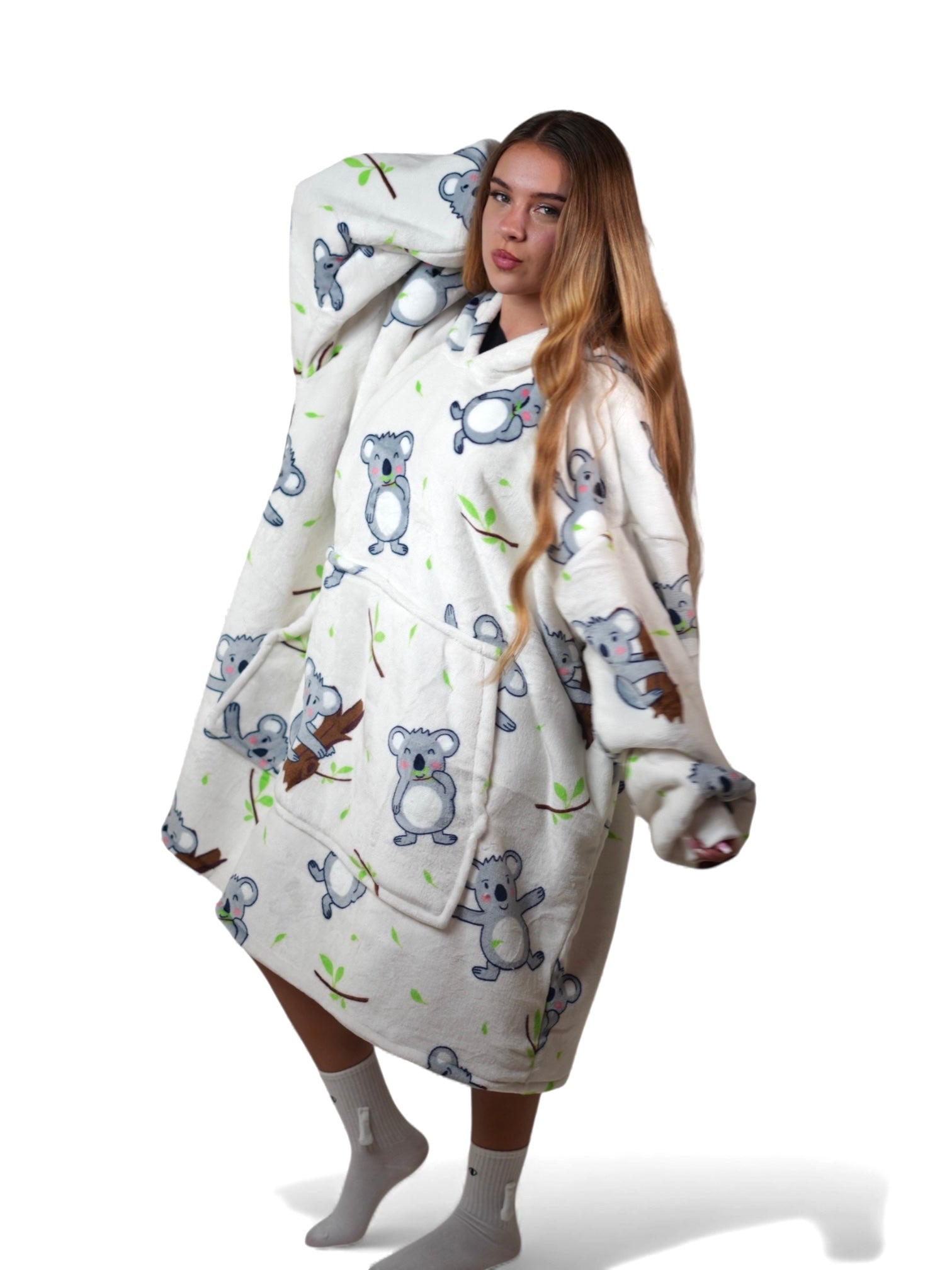 Woman wearing an off-white oversized wearable blanket hoodie with a cute koala bear print, posing close-up against a white background.